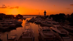 A marina at sunset with multiple yachts docked.