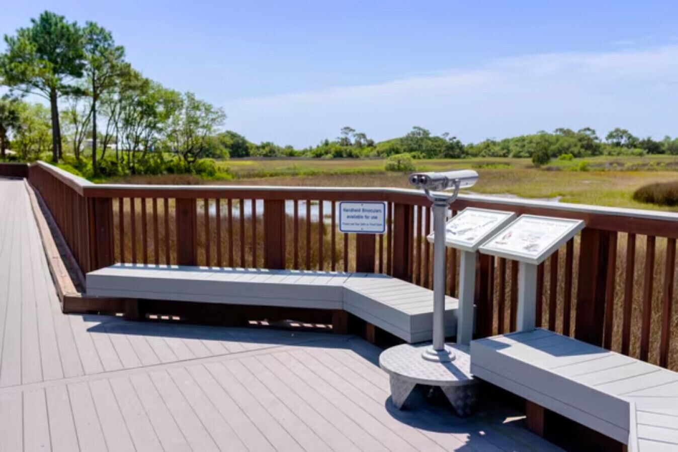 A wooden deck with a bench and a telescope, surrounded by a wooden railing and signs.