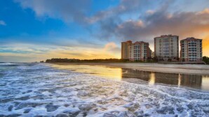 A beach with waves and a row of high-rise buildings in the background. - OceanWatch (2 Bedroom) (Myrtle Beach)