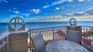 A balcony with a view of the ocean, featuring a table and chairs, and decorative metal railings. - OceanWatch (2 Bedroom) (Myrtle Beach)