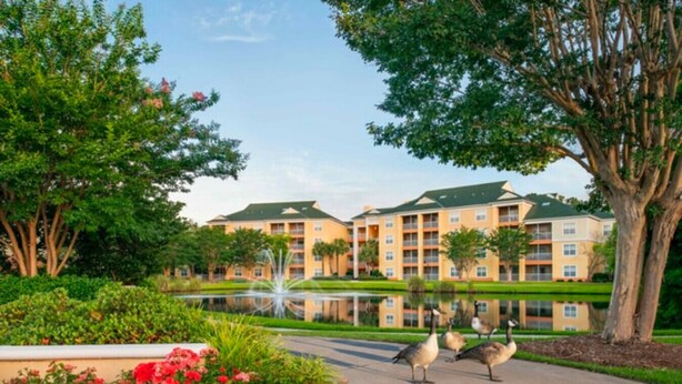 A hotel with a reflective pool, surrounded by lush greenery and red flowers. - Sheraton Broadway Resort (1BR) (Myrtle Beach)