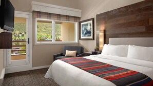 A hotel room with a large bed, a chair, a TV, and a window with a view of greenery. - Marriott's StreamSide - Birch, Douglas & Evergreen (2BR) (Vail)