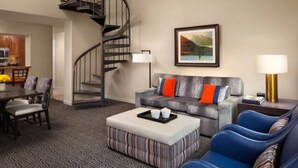A modern living room with a gray sofa, blue armchairs, a striped ottoman, and a spiral staircase. - Marriott's StreamSide - Birch, Douglas & Evergreen (2BR) (Vail)
