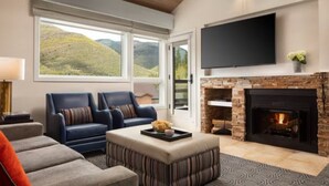 A living room with a fireplace, a sofa, a coffee table, and a TV mounted on the wall. - Marriott's StreamSide - Birch, Douglas & Evergreen (2BR) (Vail)