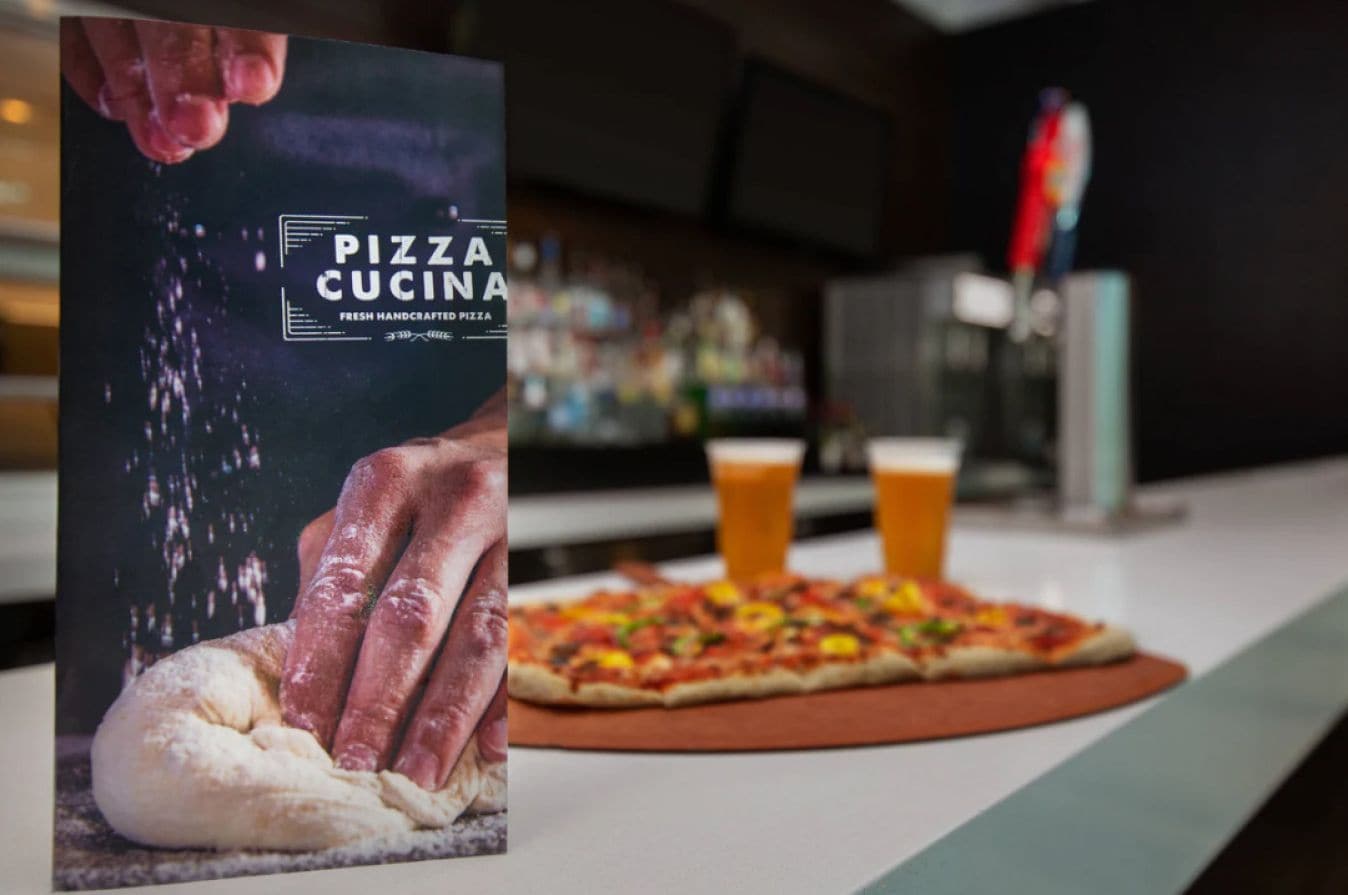 Une pizza garnie et une boisson, posées sur un comptoir.