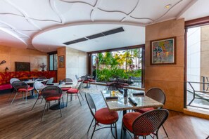 Un restaurant moderne offrant un mélange d’espaces intérieurs et extérieurs, avec un plafond incurvé et de grandes fenêtres donnant sur un jardin.