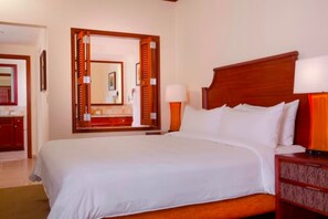 Une chambre d’hôtel avec un grand lit, une tête de lit en bois, une table de chevet avec une lampe et un miroir avec un cadre en bois.