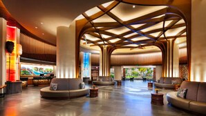 A spacious lobby with a modern design, featuring a central seating area with sofas and a large digital screen displaying a scenic image.