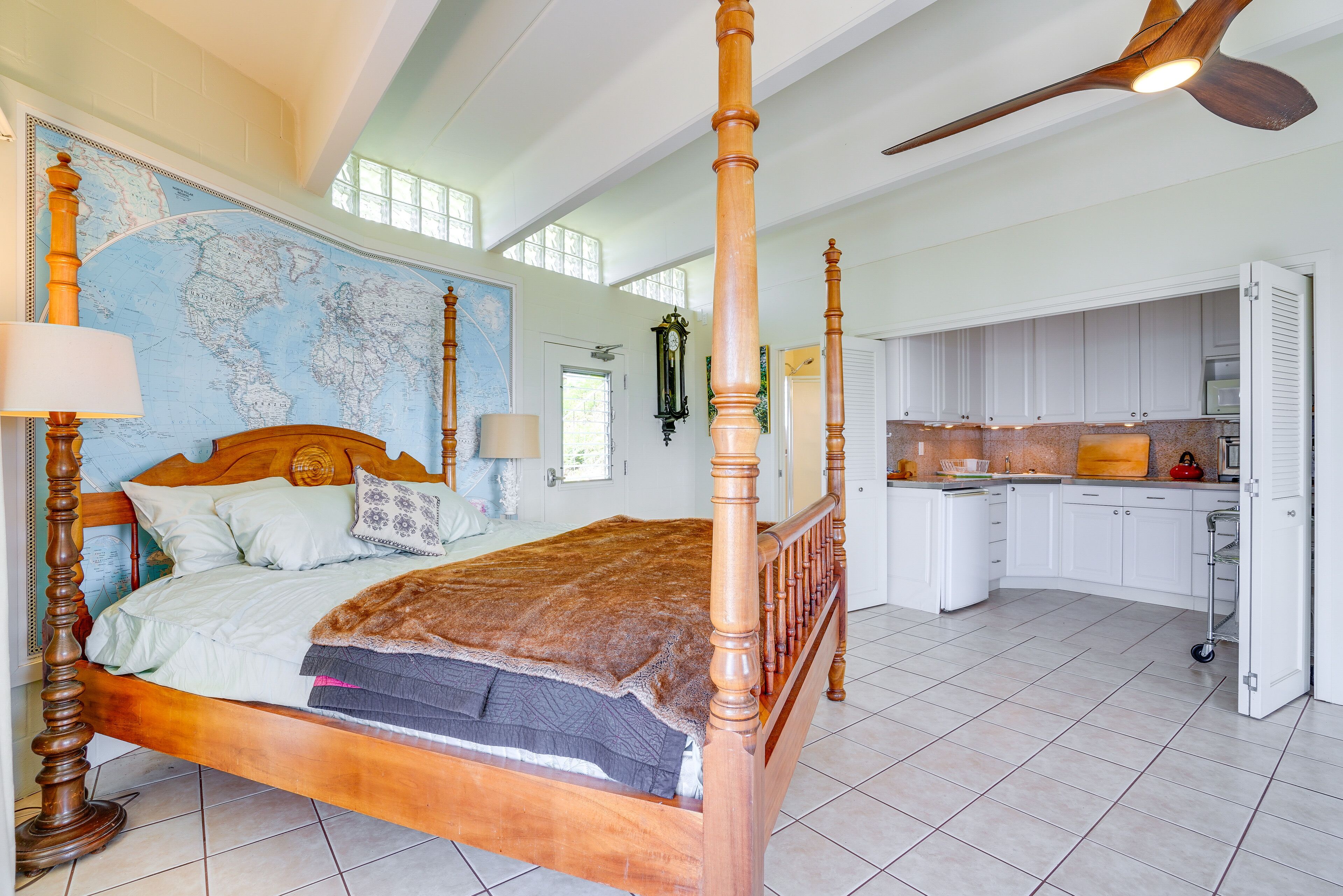Ein geräumiges Schlafzimmer mit einem großen Bett, einem hölzernen Deckenventilator und einer Weltkarte an der Wand.