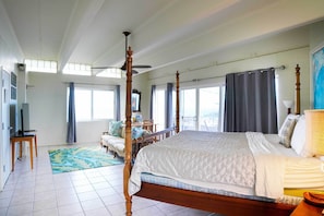 Ein geräumiges Schlafzimmer mit einem großen Bett, einem Deckenventilator und Blick auf die Stadt.