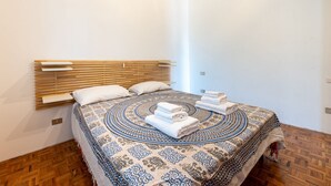 A bedroom with a bed, wooden headboard, patterned bedspread, and neatly folded towels. - Apartment located on the first mezzanine floor of a building without a lift.Immersed in the countryside, it is 15 minutes away from the center of Parma, by car.In 45 m2 of space it comfortably accommodates 4 guests with a double bedroom and a queen-size  (Parma)