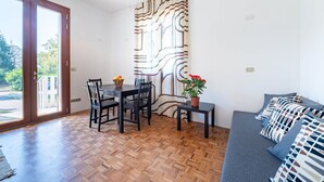 A room with a dining table, chairs, a sofa, a potted plant, and a patterned curtain. - Apartment located on the first mezzanine floor of a building without a lift.Immersed in the countryside, it is 15 minutes away from the center of Parma, by car.In 45 m2 of space it comfortably accommodates 4 guests with a double bedroom and a queen-size  (Parma)