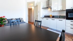 A modern kitchen with white cabinets, a stove, and a sink. There is a dining area with a table and chairs. - Apartment located on the first mezzanine floor of a building without a lift.Immersed in the countryside, it is 15 minutes away from the center of Parma, by car.In 45 m2 of space it comfortably accommodates 4 guests with a double bedroom and a queen-size  (Parma)