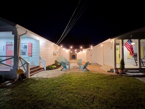 Une maison dotée d’un patio couvert, d’un espace salon extérieur et d’un drapeau américain.