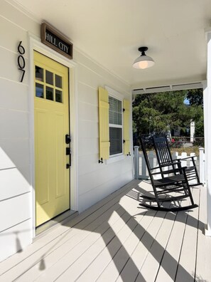 A porch with a yellow door, a sign reading "Hill City", and two rocking chairs.