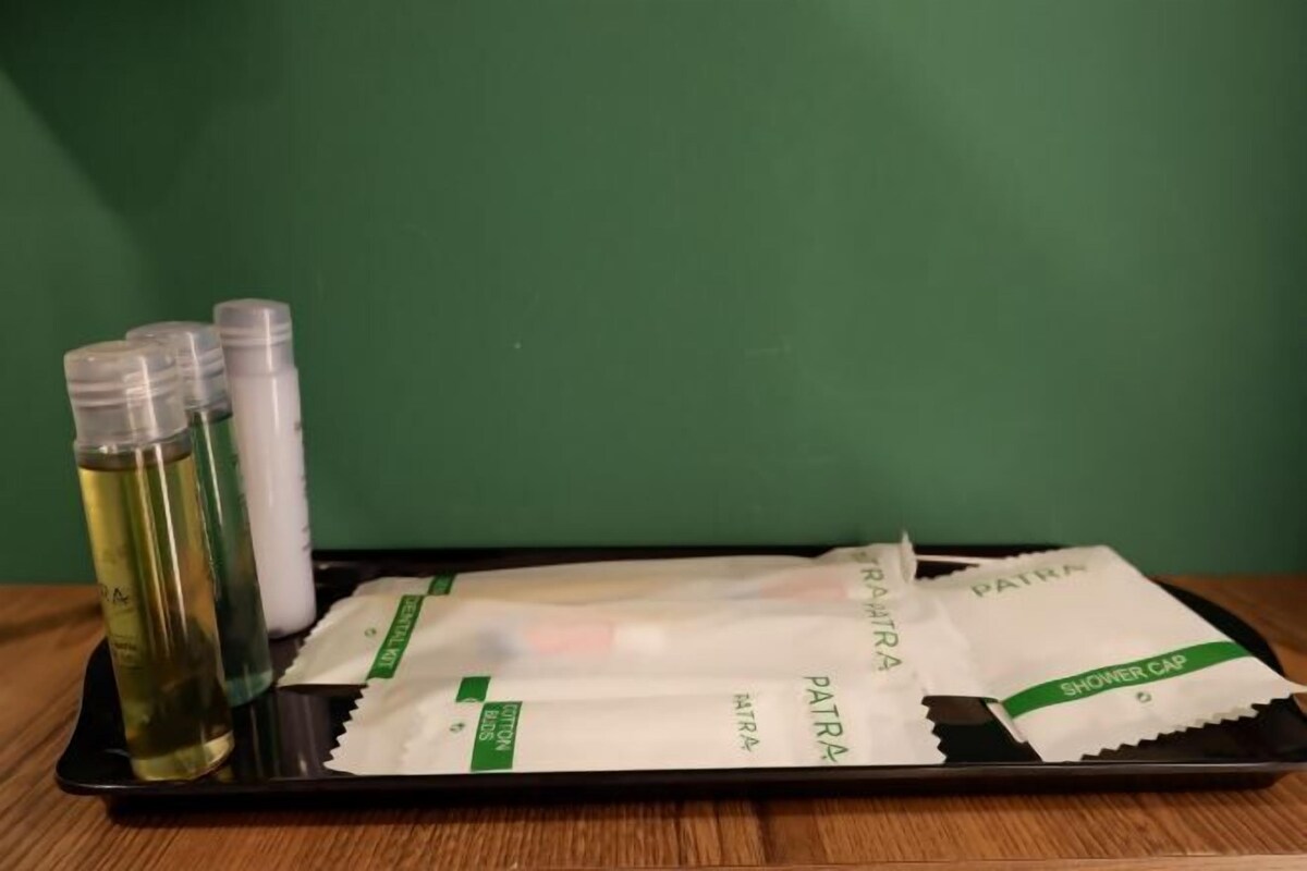 En bricka med en flaska lotion, ett tub med kräm och två förpackningar märkta med texten ”PATRIA” står på en träyta mot en grön vägg.