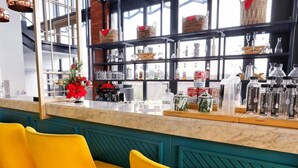 A bar area with a marble countertop, yellow bar stools, and shelves with bottles and baskets. - Patra Malioboro (Gedong Tengen)