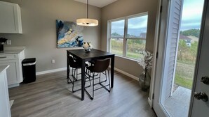A modern kitchen with a dining area, a large window with a view, and a ceiling light. - New Construction Townhome - 3 King Beds/2.5 Bathroom! (Cedar Falls)
