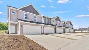 A row of single-story houses with attached garages, a clear sky, and a well-maintained driveway. - New Construction Townhome - 3 King Beds/2.5 Bathroom! (Cedar Falls)