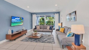 A modern living room with a sofa, coffee table, and TV. - Spacious Pool Home Close To Disney (Kissimmee)