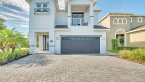 A two-story house with a garage, a balcony, and a well-maintained garden. - Spacious Pool Home Close To Disney (Kissimmee)