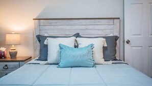 Ein Schlafzimmer mit einem Bett, Kissen, einem Nachttisch und einer Lampe.