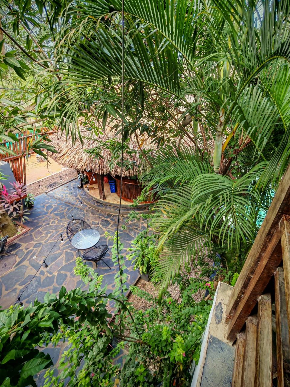 A courtyard with stone flooring, a thatched-roof structure, and outdoor seating.
