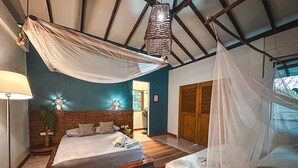 Quarto com uma cama, mesa de cabeceira, abajur e janela.