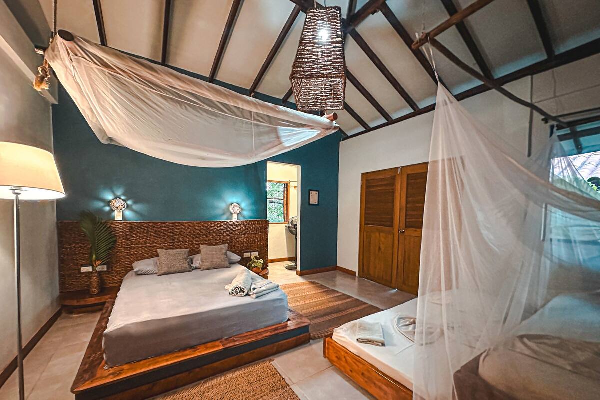 Un dormitorio con una cama, una mesita de noche, una lámpara y un ventanal.