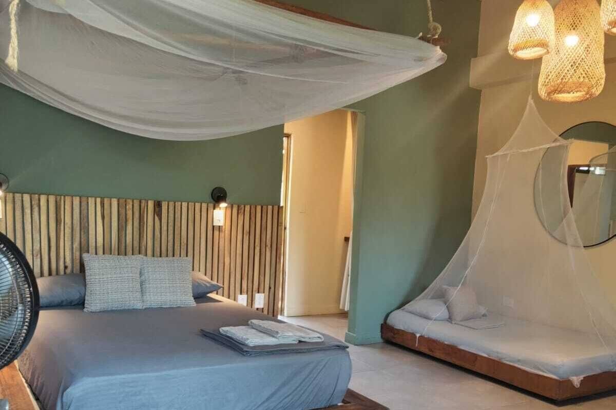 Un dormitorio con cama, mesita de noche y ventilador.