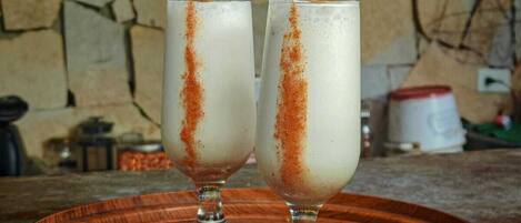Two glasses of a white beverage with a brown garnish on a wooden tray.
