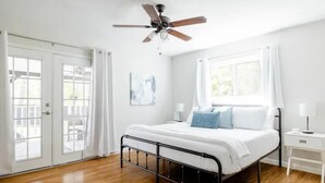 Une chambre à coucher avec un lit, un ventilateur de plafond, une table de chevet et une fenêtre.