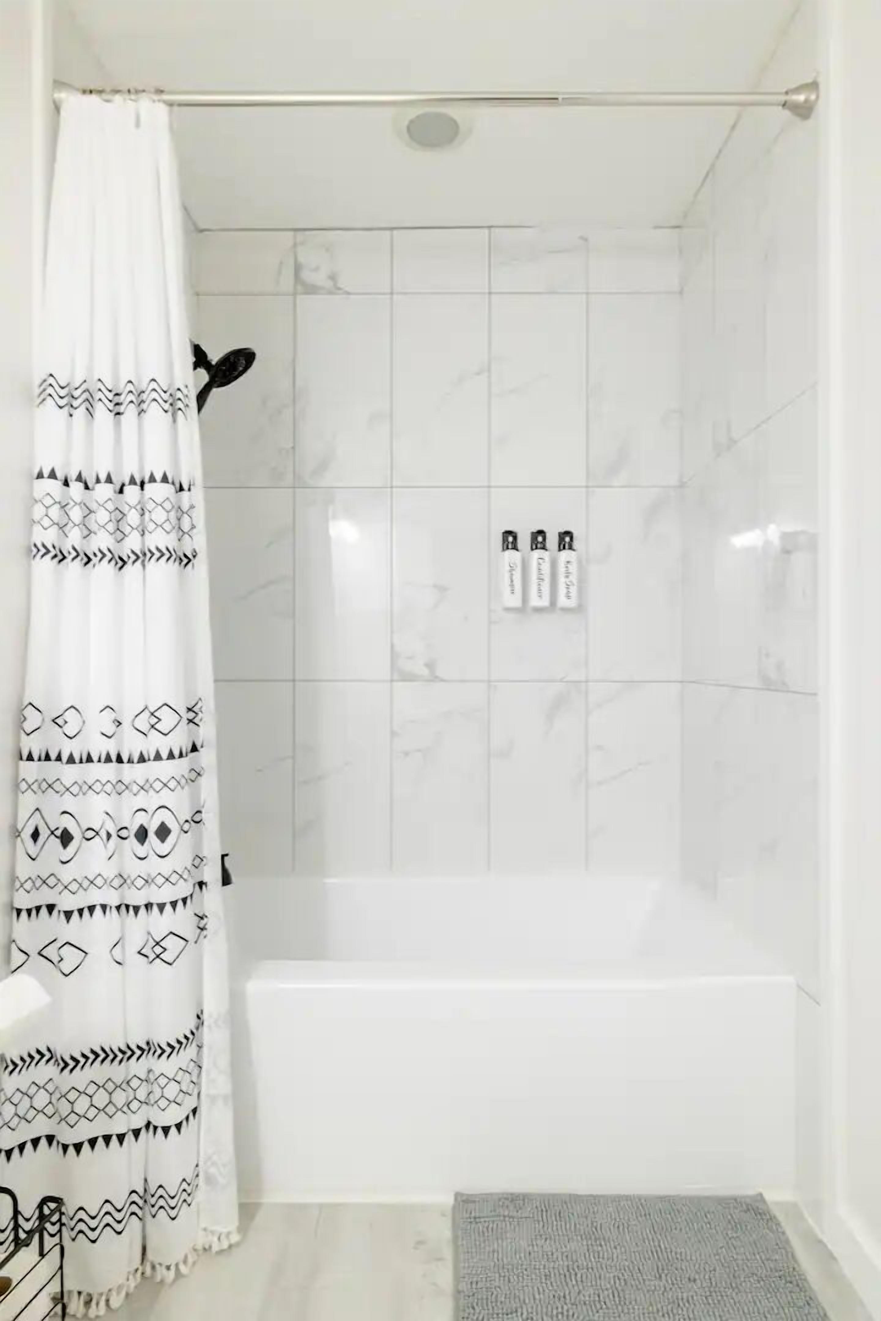 A bathroom with a shower, a bathtub, and a patterned shower curtain.