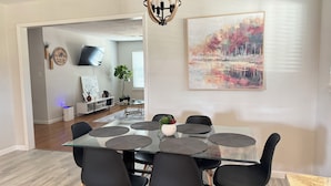 Un espace repas avec une table en verre, des chaises noires et un lustre moderne.