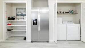 Une cuisine compacte équipée d’un réfrigérateur encastré en acier inoxydable, d’un lave-linge et d’un four à micro-ondes.