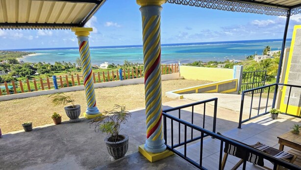 A balcony with a view of the ocean, featuring striped columns and potted plants.