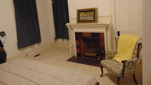 Une pièce avec une cheminée, un fauteuil à motifs et un lit.