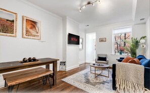 Relax in this stylish living room with a dining table, comfortable sofa, and large window.