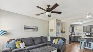 A modern living room with a sectional sofa, a coffee table, and a ceiling fan. - Bonita Beach House by Ryson Vacation Rentals (Galveston)