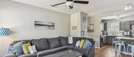A modern living room with a sectional sofa, a coffee table, and a ceiling fan.