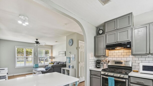 A modern kitchen with grey cabinets, a white countertop, and stainless steel appliances. - Bonita Beach House by Ryson Vacation Rentals (Galveston)