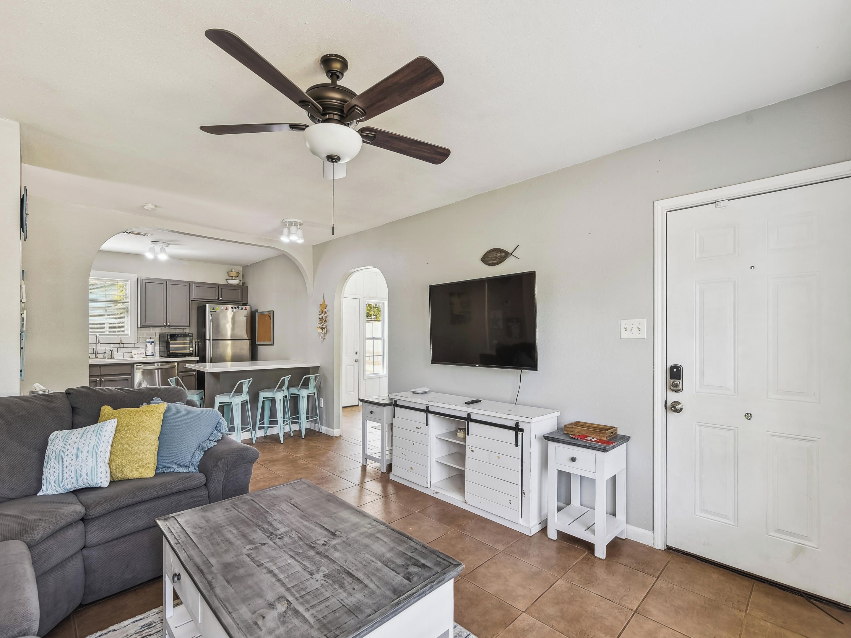 A spacious living room with a gray sofa, a wooden coffee table, and a ceiling fan.