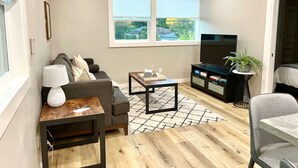 A modern living room with a sofa, coffee table, TV, and a bookshelf.