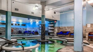 A spa area with multiple hot tubs, a central fountain, and seating areas with blue cushions.