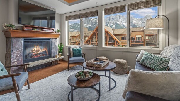 A cozy living room with a fireplace, comfortable seating, and large windows offering mountain views.