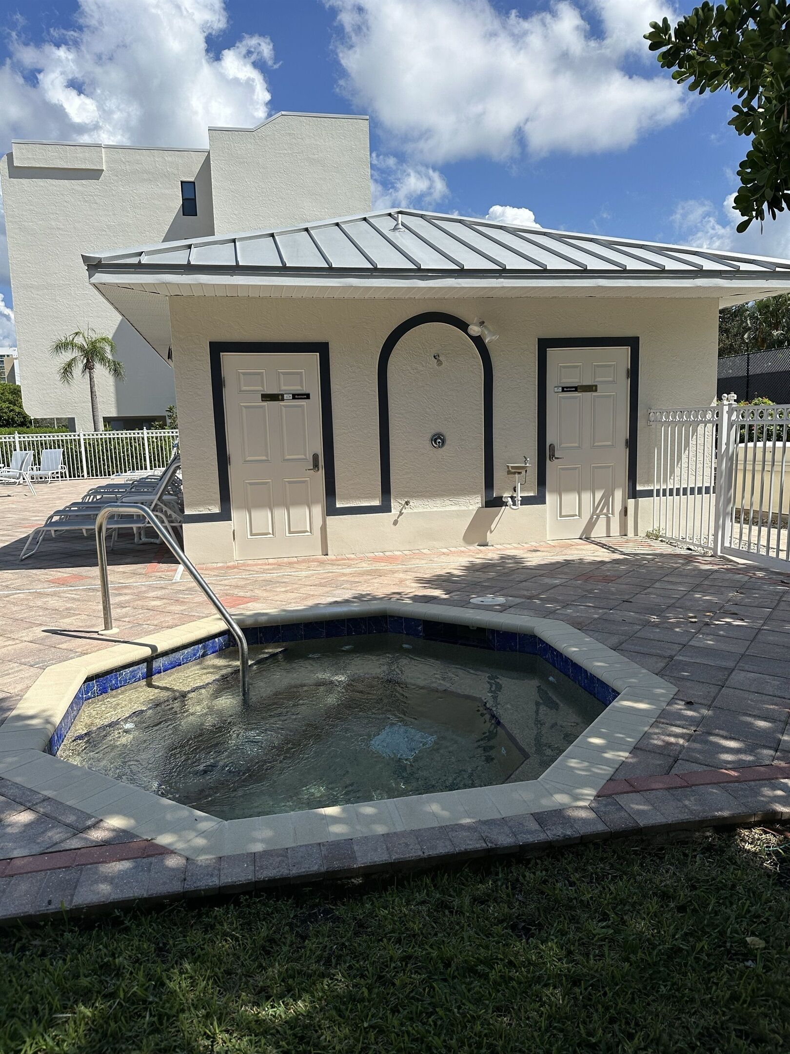 A small building with a pool, two doors, and a metal roof.