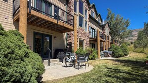 A multi-story residential building with a covered patio area, outdoor furniture, and a well-maintained lawn. - Mountain Escape in Eden, Utah (Eden)