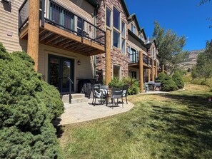A multi-story residential building with a covered patio area, outdoor furniture, and a well-maintained lawn. - Mountain Escape in Eden, Utah (Eden)