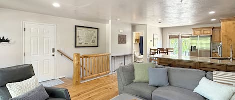 Una sala de estar moderna con un sofá gris, una mesa de centro de madera y una escalera que lleva a un nivel superior.