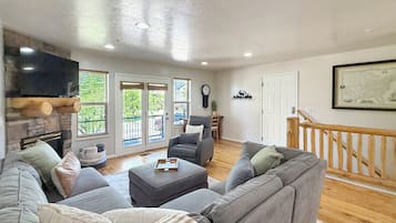 Een woonkamer met een open haard, een televisie, een bank en een eethoek.